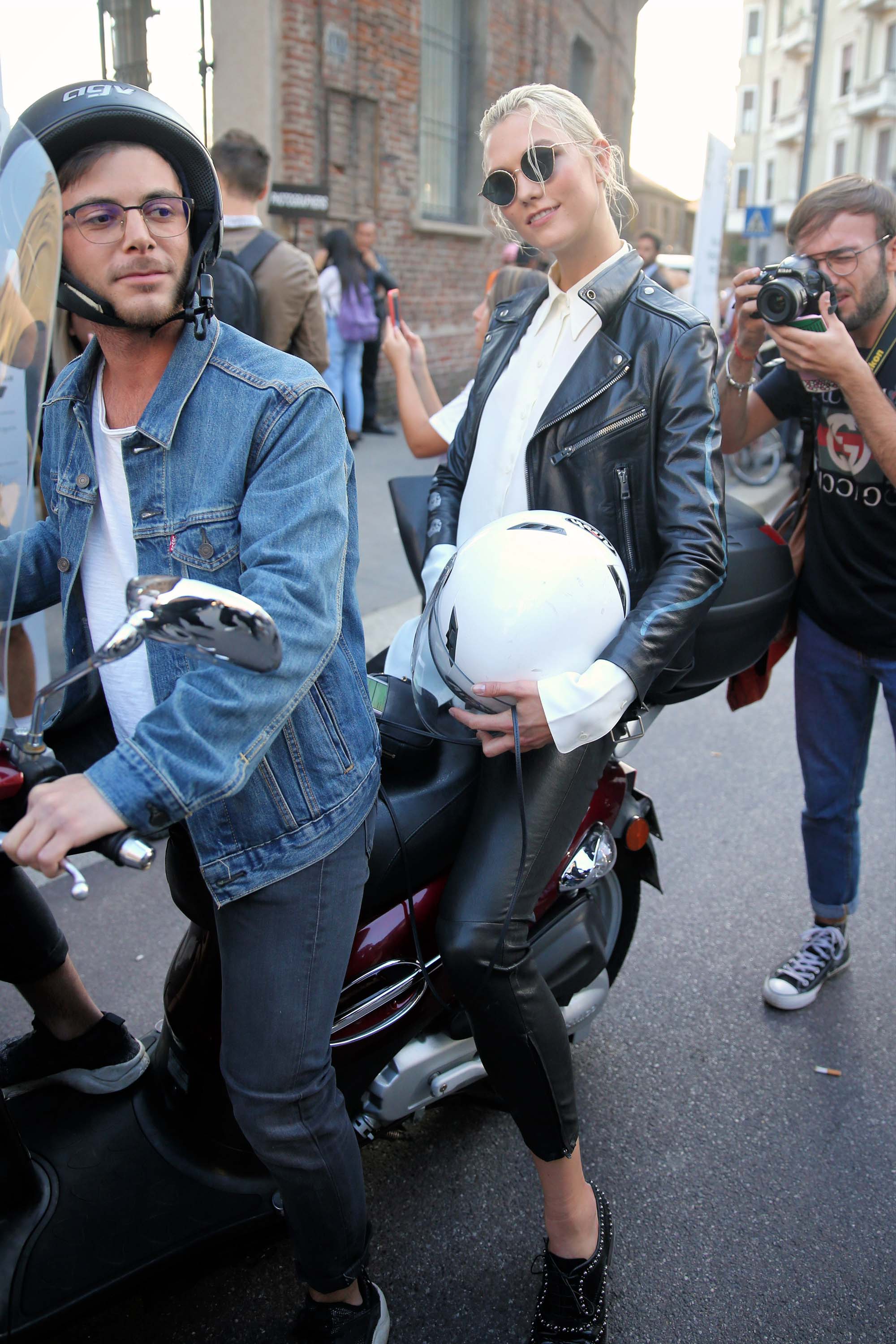 Karlie Kloss rides off on a motorcycle after walking the runway in Milan