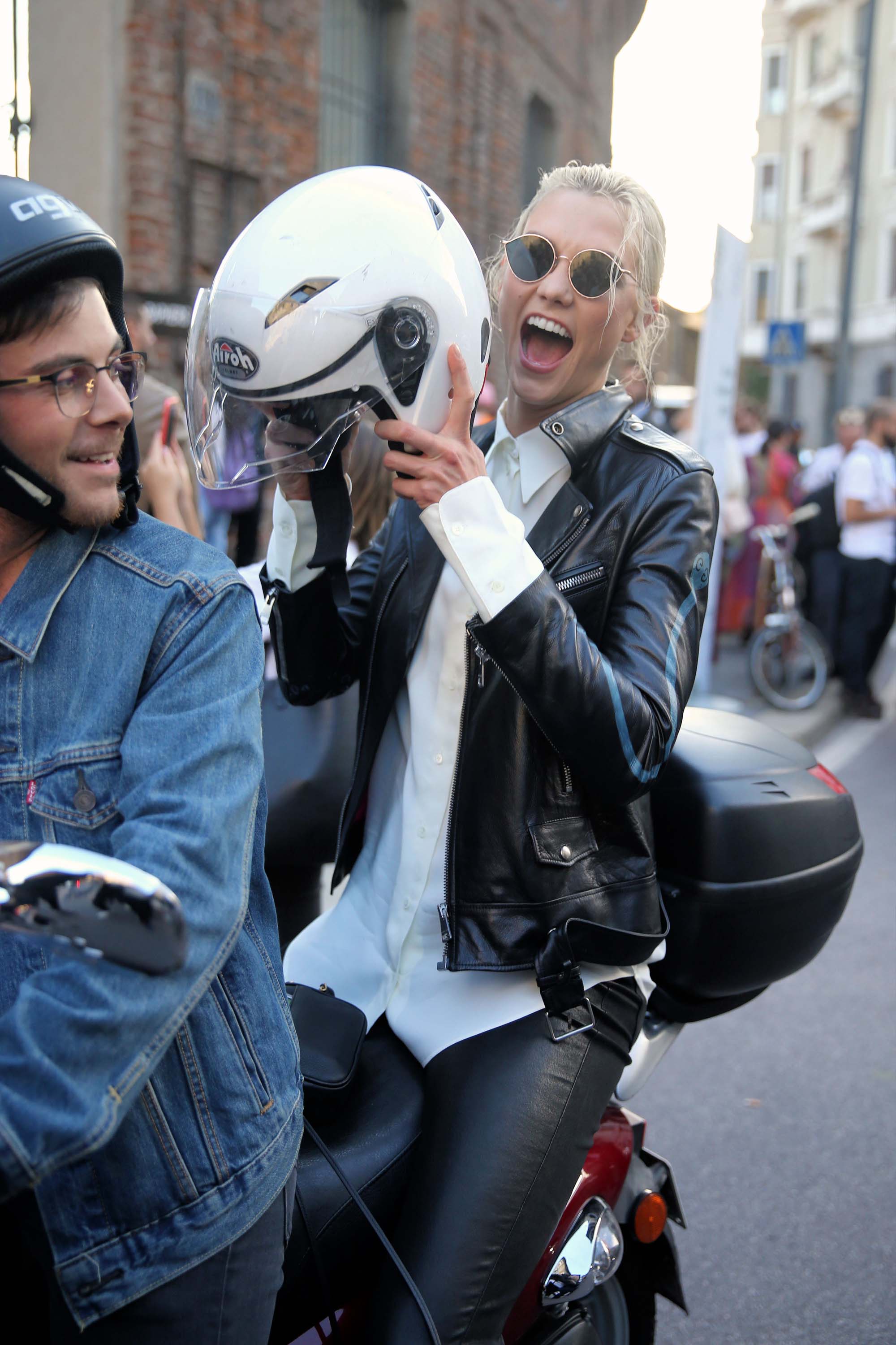 Karlie Kloss rides off on a motorcycle after walking the runway in Milan