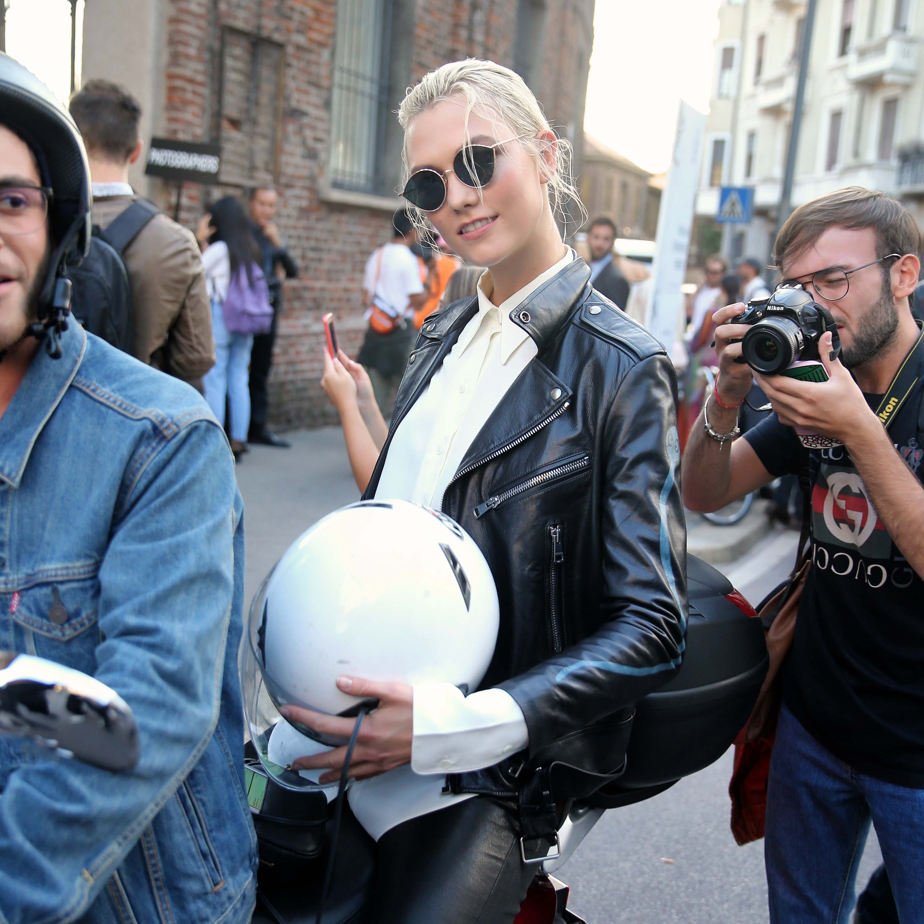 Karlie Kloss rides off on a motorcycle after walking the runway in Milan