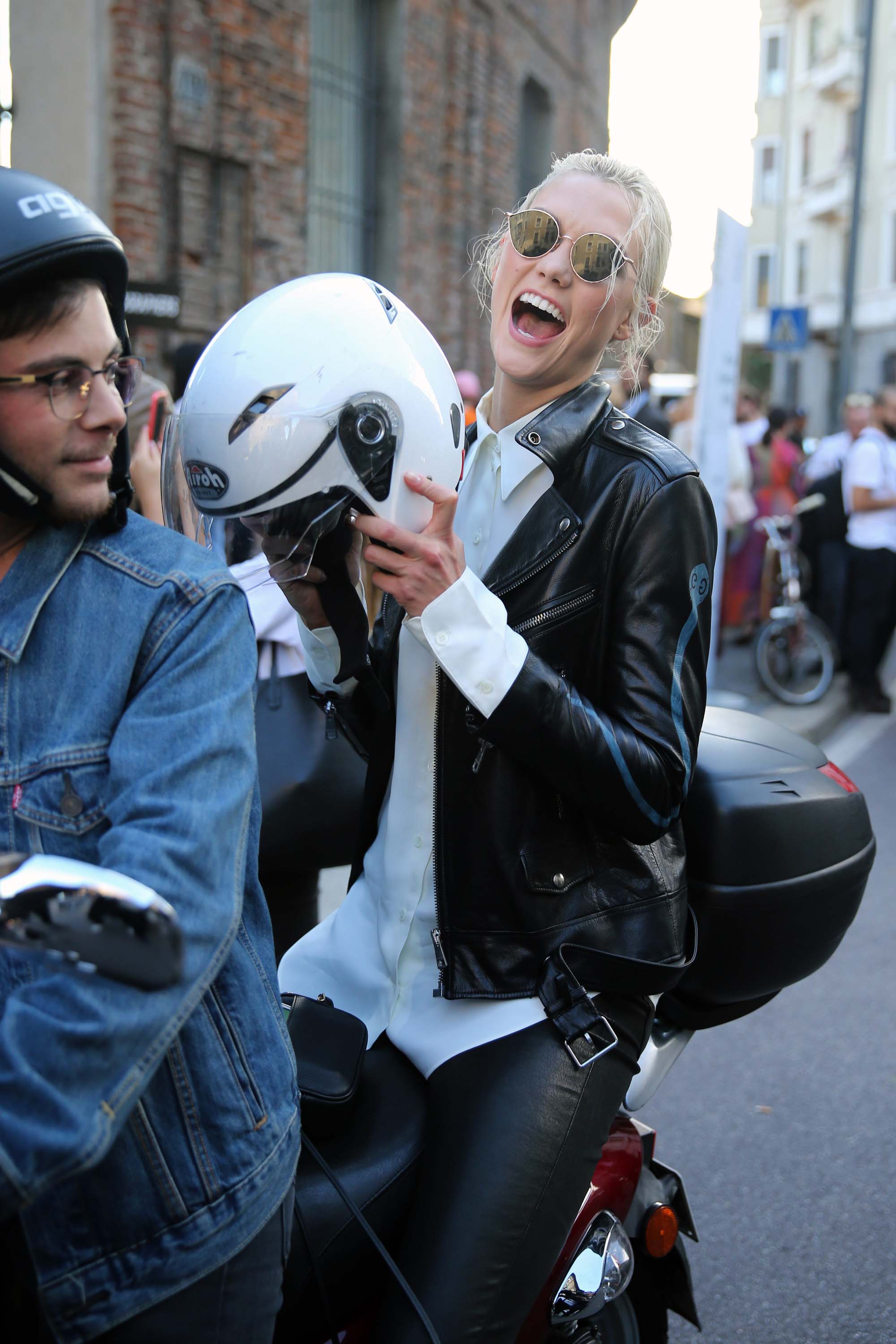 Karlie Kloss rides off on a motorcycle after walking the runway in Milan