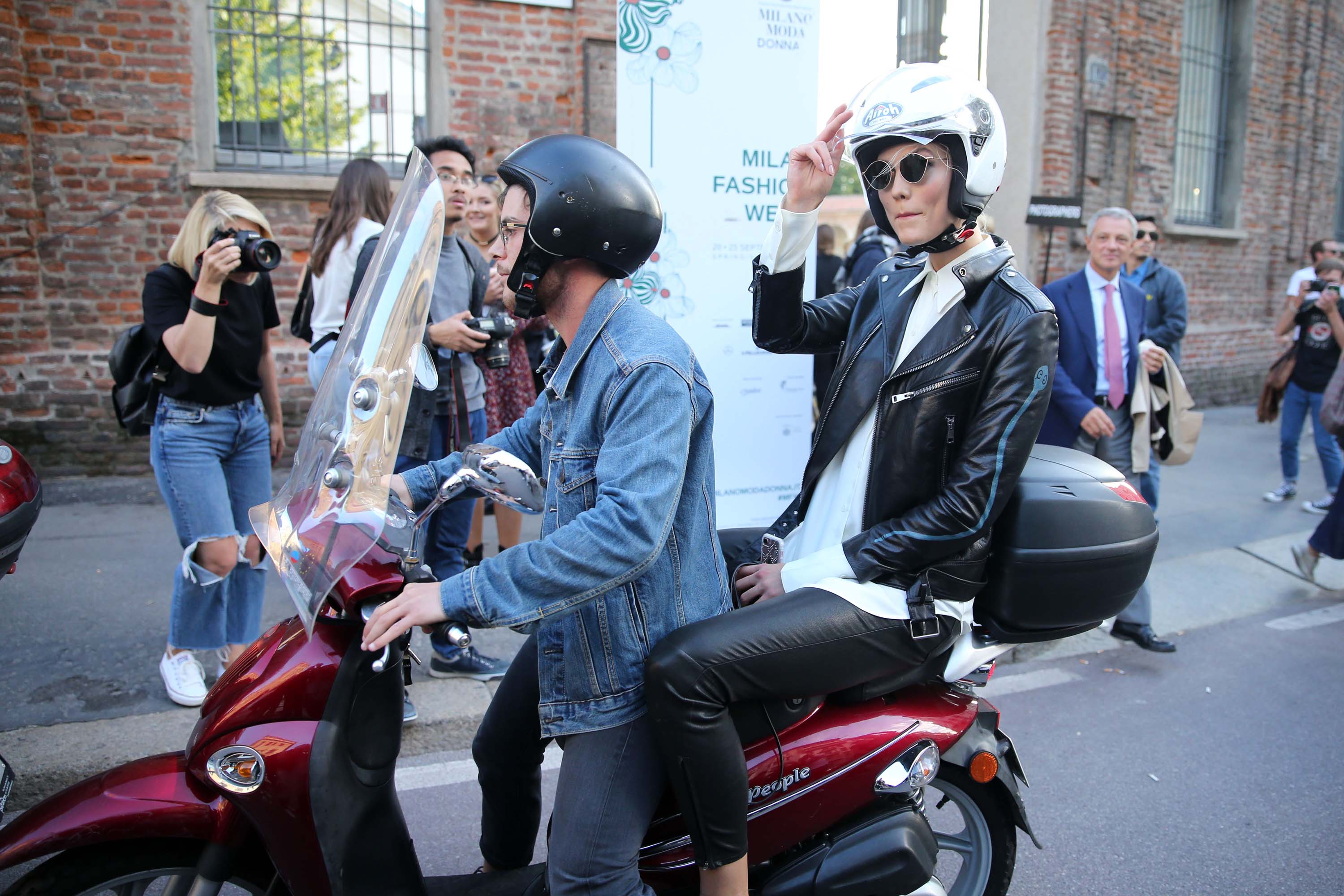 Karlie Kloss rides off on a motorcycle after walking the runway in Milan